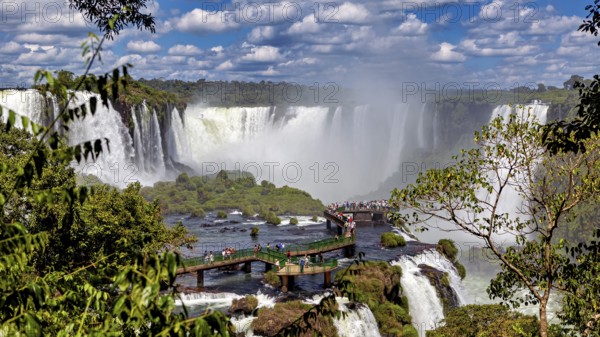 Dense vegetation surrounds a platform from which visitors can view the waterfalls, The Iguazu Falls between Argentina and Brazil