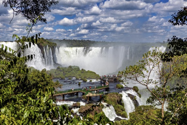 Green jungle and dramatic waterfalls, visitors on a wooden platform, The Iguazu Falls between Argentina and Brazil