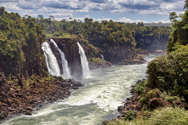 Two waterfalls plunge into a river, surrounded by a green and rocky landscape, The Iguazu Falls between Argentina and Brazil
