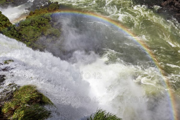 A glowing rainbow appears over a thundering waterfall, The Iguazu Falls between Argentina and Brazil