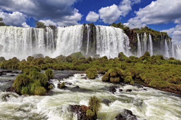 A spectacular waterfall plunges down in the middle of a green and lush landscape, The Iguazu Falls between Argentina and Brazil