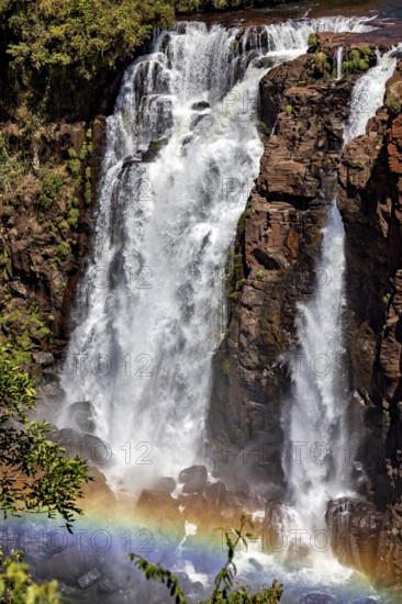 Impressive waterfall with rainbow in front of a rocky wall, The Iguazu Falls between Argentina and Brazil