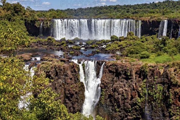 Spectacular waterfall flows over rocky cliffs in lush natural surroundings, The Iguazu Falls between Argentina and Brazil
