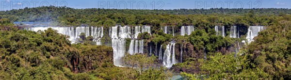 Sweeping view of the waterfalls with flowing river and green forest, The Iguazu Falls between Argentina and Brazil