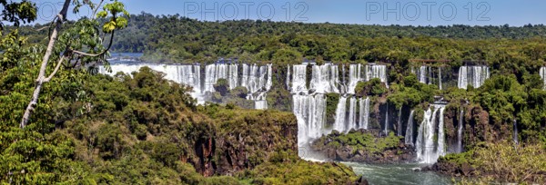 Sweeping panorama of the waterfalls with dense forest in the background, The Iguazu Falls between Argentina and Brazil