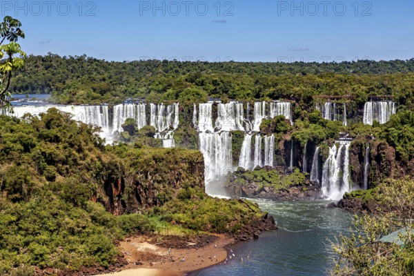 Impressive view of majestic waterfalls with a small sandy beach, The Iguazu Falls between Argentina and Brazil