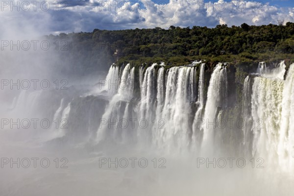 Mysterious waterfalls in the mist, surrounded by a forested area and overcast skies, The Iguazu Falls between Argentina and Brazil