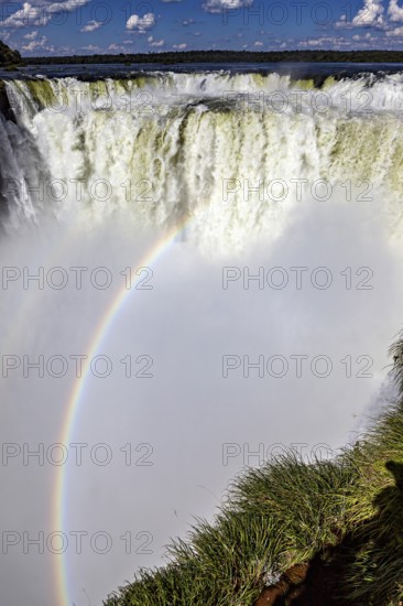 Dramatic waterfall with rainbow and spray under a blue sky, The Iguazu Falls between Argentina and Brazil