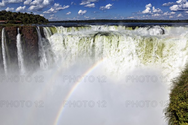 Majestic waterfall with rainbow and spray under a cloudy sky, The Iguazu Falls between Argentina and Brazil