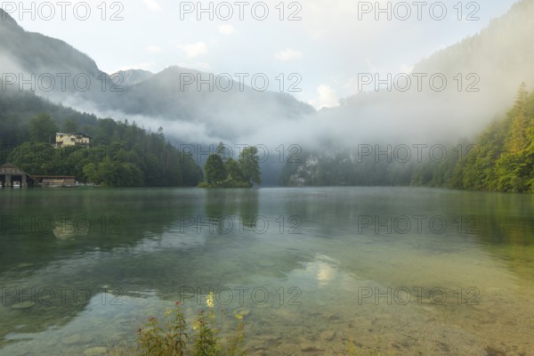 Mystical morning at Königssee in Schönau with boathouses and Christlieger. Sunrise and beautiful wafts of mist over the Königssee in the basin