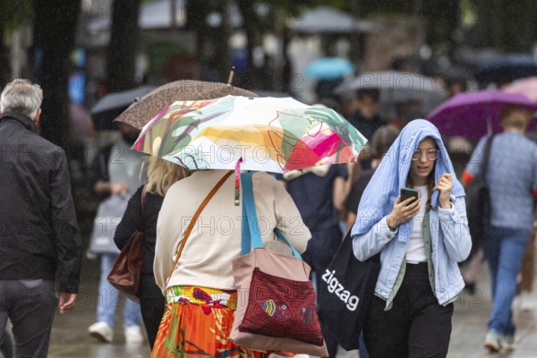 Rainy weather in Stuttgart. People with umbrellas hurry through the rain on Königstraße. Stuttgart, Baden-Württemberg, Germany
