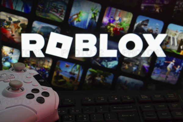 Dhaka, Bangladesh- 26 July 2025: A close-up of a white gamepad with The Roblox seen on screen in the background