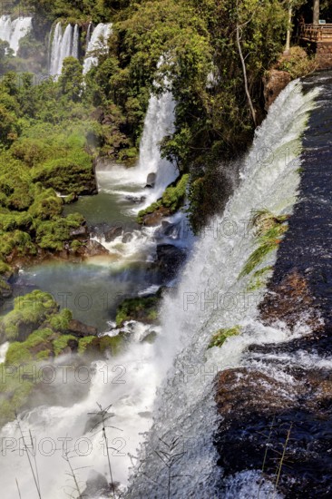 View from a cliff of cascading waterfalls and rainbow in the river below, The Iguazu Falls between Argentina and Brazil