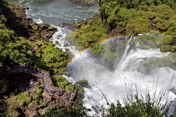 Viewing platform with visitors over a waterfall and rainbow, The Iguazu Falls between Argentina and Brazil