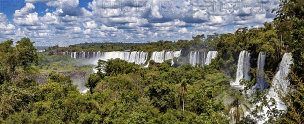 Wide panorama of waterfalls in the middle of a tropical jungle under a cloudy sky, The Iguazu Falls between Argentina and Brazil