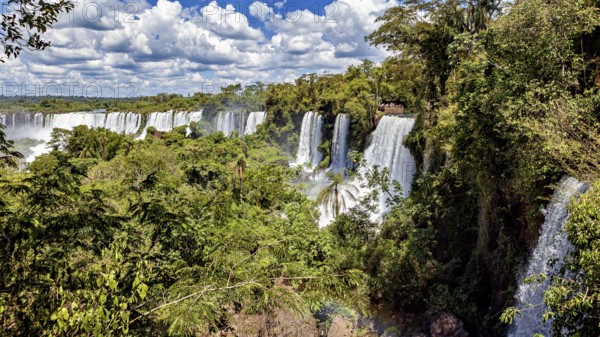Sweeping views of several waterfalls that run through dense vegetation and reach the sky, The Iguazu Falls between Argentina and Brazil