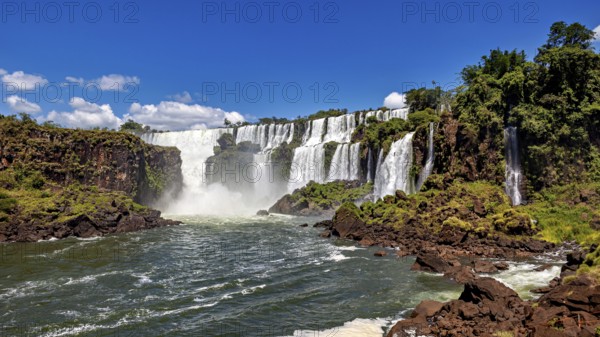 Impressive waterfalls with cascading floods and lush vegetation under a blue sky, The Iguazu Falls between Argentina and Brazil