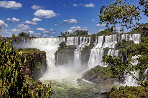Waterfalls with rich vegetation and spray under a cloudy sky, The Iguazu Falls between Argentina and Brazil