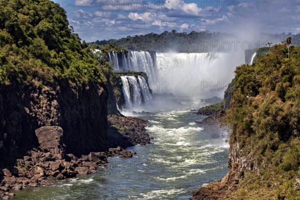 Majestic waterfalls with strong flow and spray, framed by lush vegetation, The Iguazu Falls between Argentina and Brazil
