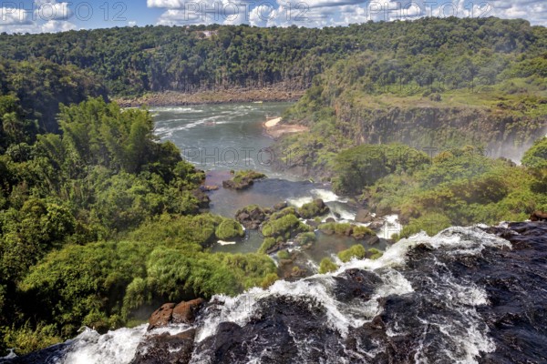 View along a cliff over a river with lush vegetation in the background, The Iguazu Falls between Argentina and Brazil