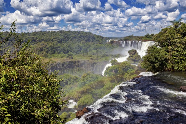 View over the waterfall and wooded surroundings under a cloudy sky, The Iguazu Falls between Argentina and Brazil