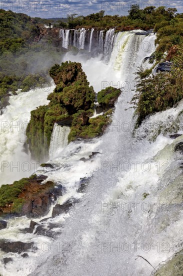 Dramatic waterfall with strong spray, surrounded by green vegetation and rocks, The Iguazu Falls between Argentina and Brazil