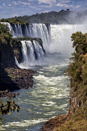 Impressive waterfalls with strong currents, surrounded by rocks and lush vegetation, The Iguazu Falls between Argentina and Brazil