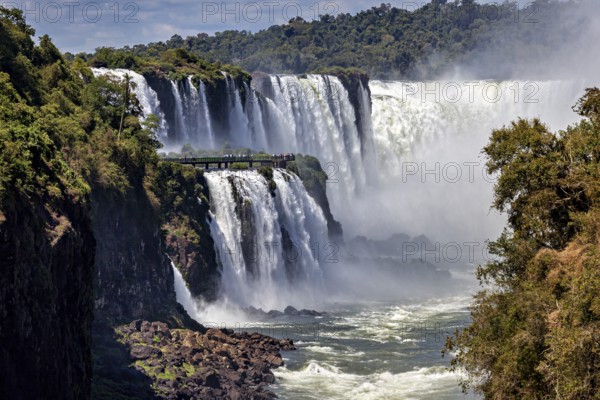 Majestic waterfalls with observation bridge, large river and lush forest backdrop, The Iguazu Falls between Argentina and Brazil