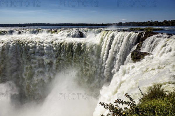Thundering waterfall with spray and blue sky, The Iguazu Falls between Argentina and Brazil