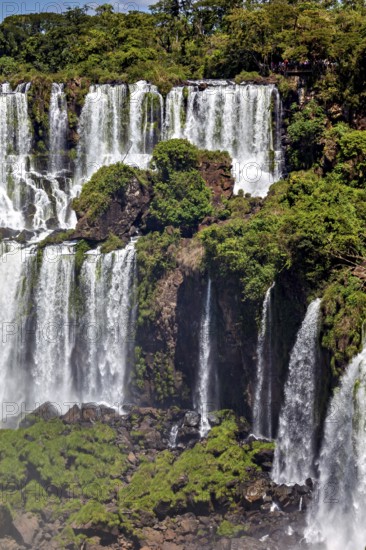 Steep, living waterfalls with lush green vegetation and large rocks, The Iguazu Falls between Argentina and Brazil