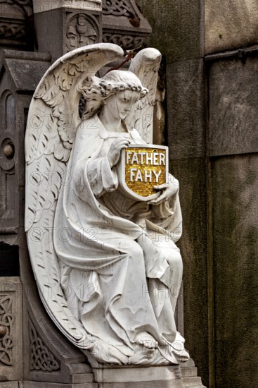 A sculpture of an angel holds a sign with an inscription, richly detailed, La Recoleta cemetery in Buenos Aires Argentina