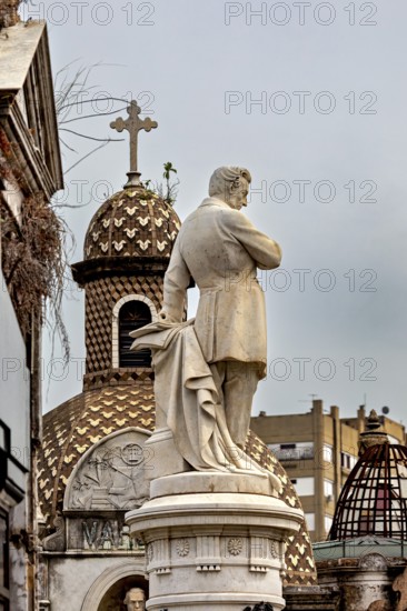 Marble sculpture in front of a decorative dome with a cross in an urban setting, La Recoleta cemetery in Buenos Aires Argentina
