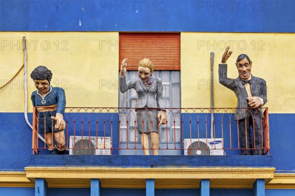 Three figures on a balcony of a historically painted building, The colourful city and tango district La Bocca in Buenos Aires Argentina