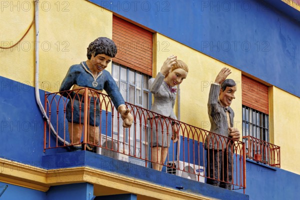 Figures on a balcony of a blue and yellow building in La Boca, the colourful city and tango district of La Bocca in Buenos Aires Argentina