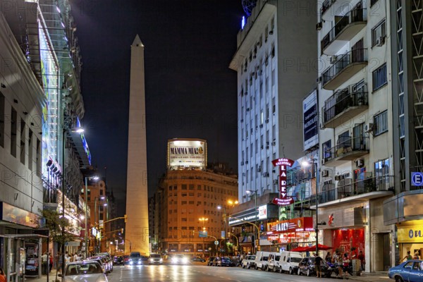 Night scene in a busy shopping street with the obelisk illuminated in the distance, The Great Obelisk in the city of Buenos Aires Argentina