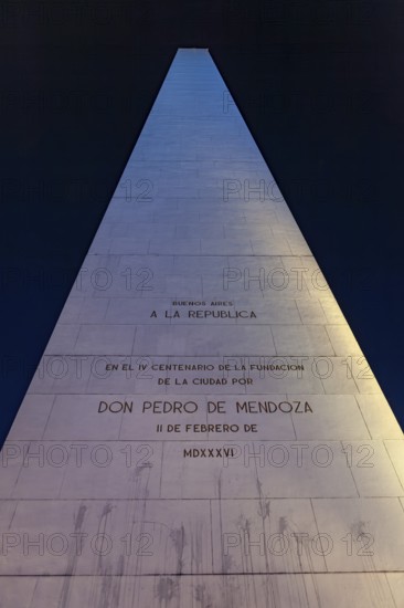 An illuminated obelisk with inscriptions in Buenos Aires at night against a deep blue sky, The large obelisk in the city of Buenos Aires Argentina