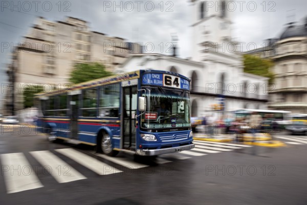 A blurred bus in motion on a city street in front of a church, The bus line 64 in the city of Buenos Aires in Argentina