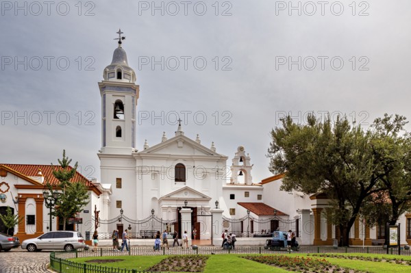 White church with bell tower and people in the forecourt in a quiet neighbourhood, La Recoleta cemetery in Buenos Aires Argentina