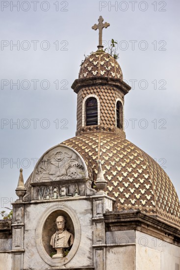 Historic structure with decorative dome, cross and a bust in an ornate relief, La Recoleta cemetery in Buenos Aires Argentina