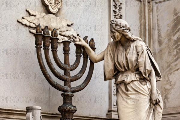Stone statue of a woman touching a candlestick, artistic and detailed, La Recoleta cemetery in Buenos Aires Argentina