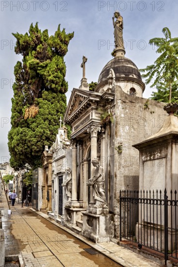 Magnificent burial site with trees and statues along a path, La Recoleta cemetery in Buenos Aires Argentina