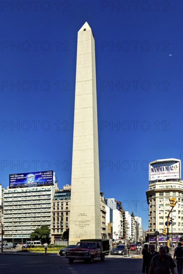 An obelisk in sunny weather in a busy city centre with traffic in the foreground, The large obelisk in the city of Buenos Aires Argentina