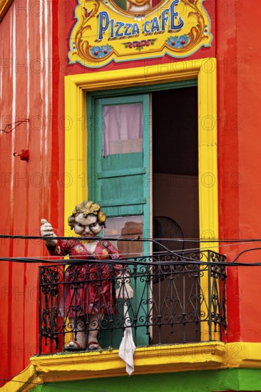 A humorous sculpture of a woman on a balcony in front of a colourful building, The colourful city and tango district La Bocca in Buenos Aires Argentina