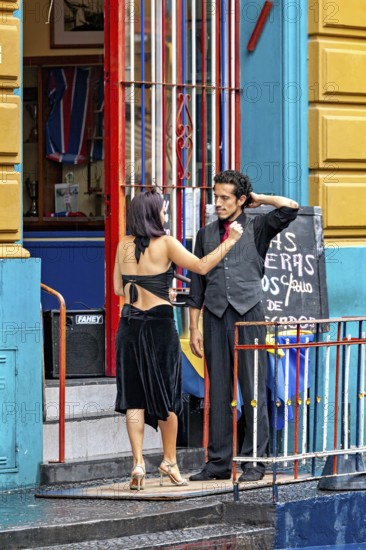 A couple discussing in front of a colourful entrance in tango clothes, the woman wears a black dress, The colourful city and tango district La Bocca in Buenos Aires Argentina