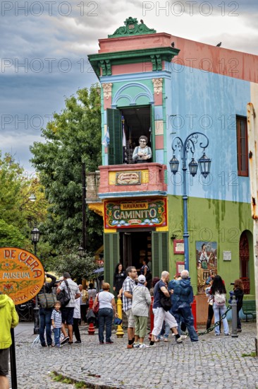 A lively place with colourful buildings and people, a statue stands on the balcony, The colourful city and tango district La Bocca in Buenos Aires Argentina