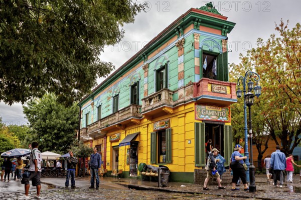 A colourful historic building with cafés attracts people on a cobbled street, The colourful city and tango district of La Bocca in Buenos Aires Argentina