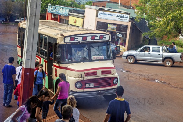 A bus stops in a suburban area, surrounded by people and vehicles, An old Mercedes bus in Argentina