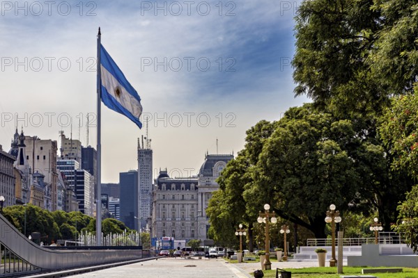 A large flag flies in front of an urban landscape with historic buildings and trees, The city of Buenos Aires in Argentina