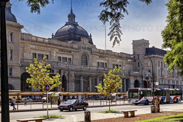 A historic railway station with a domed roof, surrounded by cars and trees in daylight, The city of Buenos Aires in Argentina