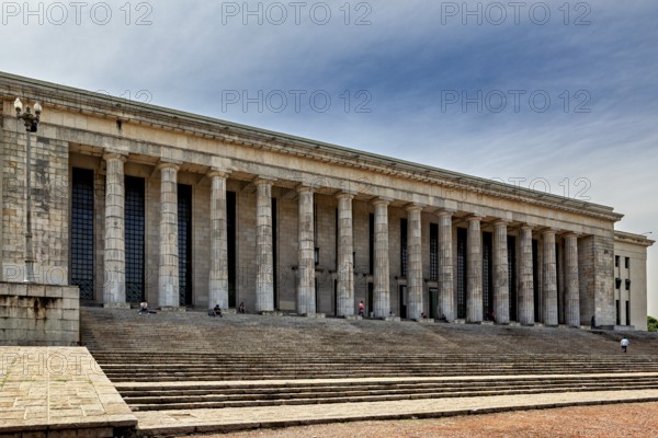 A wide building with many columns and large stairs in front of a slightly cloudy sky, The city of Buenos Aires in Argentina